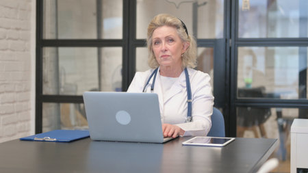 Senior Female Doctor Looking at Camera in Hospitalの写真素材
