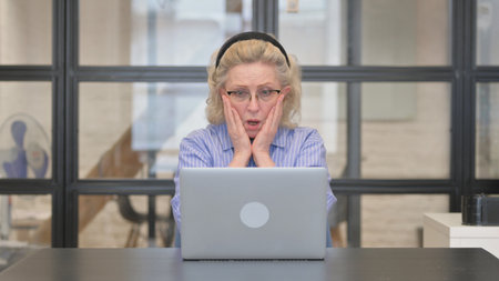 Casual Old Woman Reacting to Online Loss at Workの写真素材