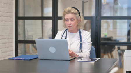 Senior Female Doctor Typing on Laptop in Hospitalの写真素材