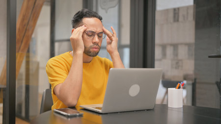 Creative Mixed Race Man having Headache at Work