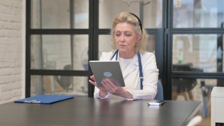 Senior Female Doctor Using Digital Tablet for Work in Hospitalの写真素材