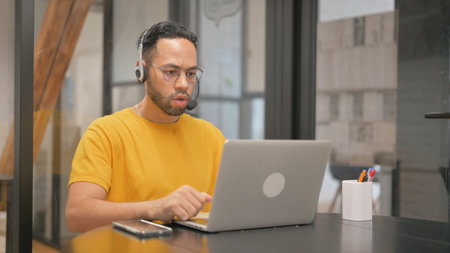 Creative Mixed Race Man with Headset Doing Video Chat via Laptop