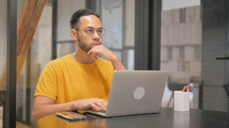 Pensive Creative Mixed Race Man Using Laptop