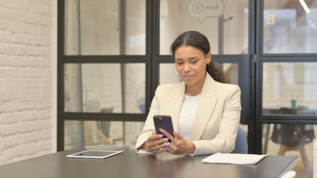 African Woman Doing Video Chat on Phone in Officeの写真素材