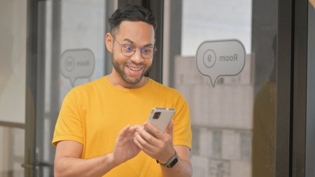 Portrait of Casual Young African Man Celebrating Success on Phone