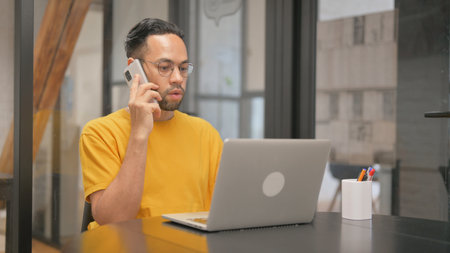 Creative Mixed Race Man Talking on Phone at Work