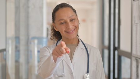 Portrait of Multiracial Female Doctor Pointing at Cameraの写真素材