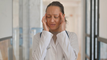 Portrait of Multiracial Female Doctor with Headache in Office