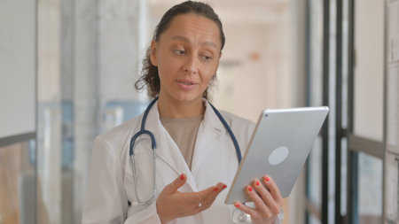 Portrait of Multiracial Female Doctor Doing Video Chat on Tabletの写真素材