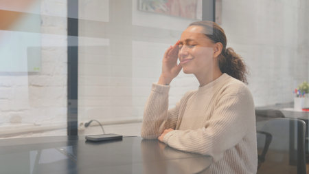 Tense Multiracial Woman with Migraine at Workspace