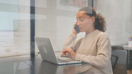 Multiracial Woman Talking on Phone at Workspace