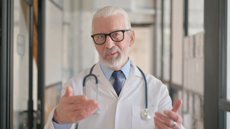 Senior Male Doctor Doing Video Chat in Hospitalの写真素材