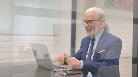 Senior Businessman Doing Video Chat via Laptopの写真素材