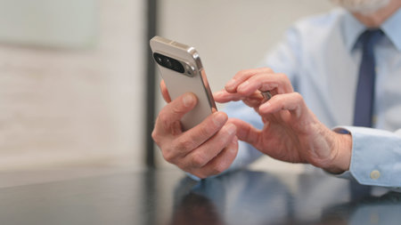 Close up of Old Businessman Browsing Internet on Phone in Office