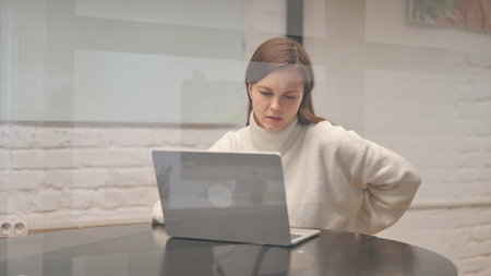 Young Woman having Back Fatigue and Pain at Workspaceの写真素材