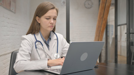 Young Female Doctor Typing on Laptopの写真素材
