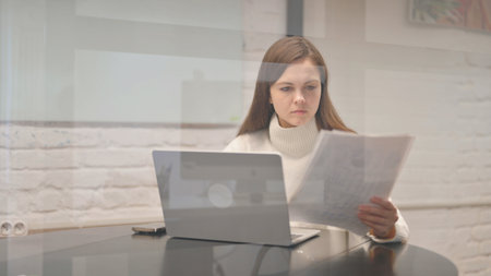Young Woman Working on Documents and Laptopの写真素材