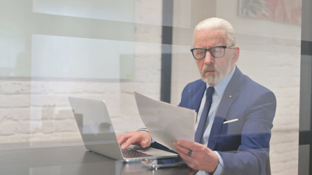 Senior Businessman Working on Documents and Laptopの写真素材