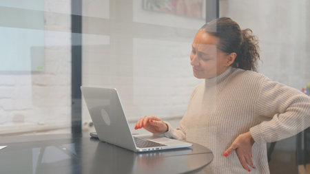 Multiracial Woman having Back Fatigue and Pain at Workspaceの写真素材