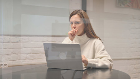 Sick Young Woman Coughing at Workspace