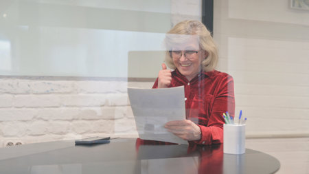 Excited Senior Old Woman Celebrating New Reportの写真素材
