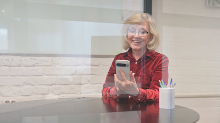 Portrait of mature businesswoman using mobile phone at table in office