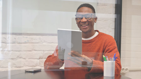 African Man Doing Video Chat on Tablet at Workspace