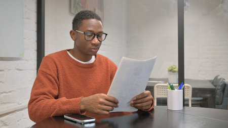 Young African American man working with documents at home office.の写真素材