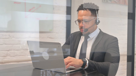 Hispanic Businessman with Headset in Call Center Typing on Laptopの写真素材