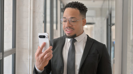 Portrait of Hispanic Businessman Doing Video Chat on Phoneの写真素材