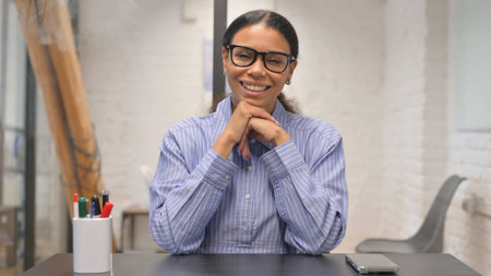 Portrait of happy young businesswoman in eyeglasses looking at camera in officeの写真素材