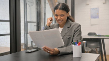 Excited African American Businesswoman Celebrating Annual Business Reportの写真素材