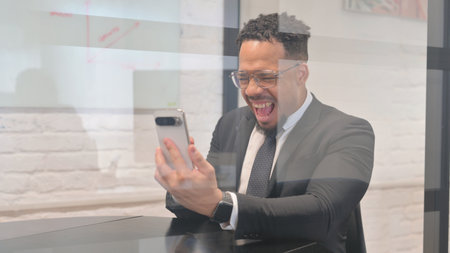 Hispanic Businessman Excited for Online Successful Trade on Phoneの写真素材