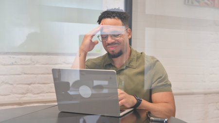 Multiracial Man having Headache while using Laptopの写真素材