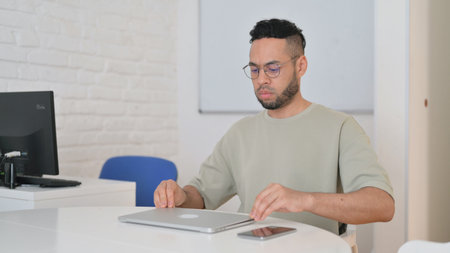 Hispanic Man Leaving Workspace, Getting Late for Meeting