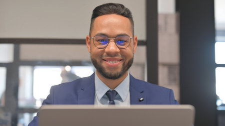 Close up of Hispanic Businessman Smiling at Camera at Workspace
