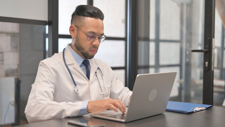 Hispanic Doctor Typing on Laptopの写真素材
