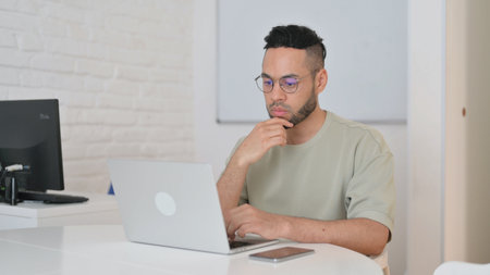 Pensive Hispanic Man Brainstorming for Projectの写真素材