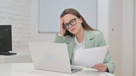 Upset Business Woman Working on Laptop and Documentsの写真素材