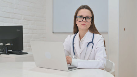 Young Doctor Typing Message on Phone in Clinicの写真素材