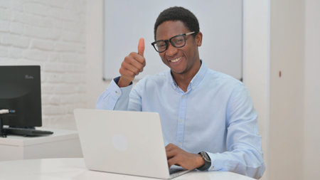 Thumbs up by Young African Businessman Working on Laptop