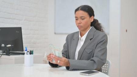 African Business Woman Counting Money in Officeの写真素材