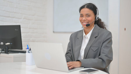 Woman with Headset in Call Center Smiling at Camera at Workspaceの写真素材