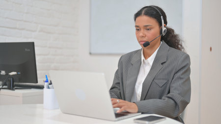 Woman with Headset in Call Center Typing on Laptop