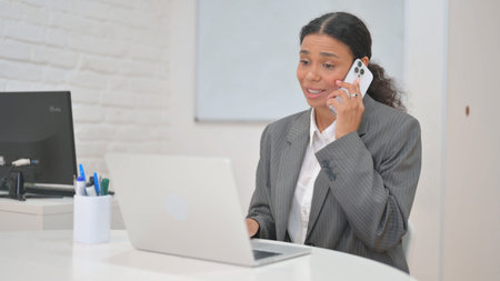 African Business Woman Talking on Phone at Workspaceの写真素材