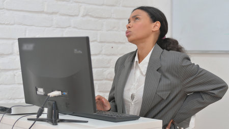 African Business Woman with Back Pain Working on Desktop Computerの写真素材
