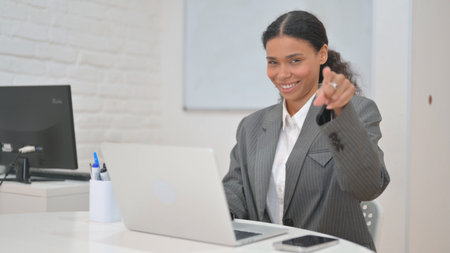 African Business Woman Pointing at Camera While Working on Laptopの写真素材