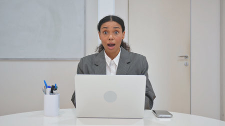 Surprised African Business Woman Looking at Camera with Excitementの写真素材
