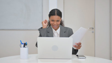 Woman Celebrating while Working on Laptop and Documents