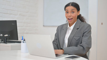 Surprised African Business Woman Looking at Camera with Excitementの写真素材